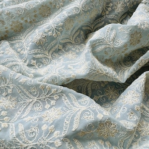 May include: A light blue fabric with a white floral embroidery pattern.