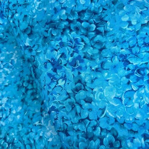 May include: A close-up of a blue fabric with a floral pattern. The fabric is covered in small, blue flowers.