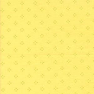 May include: A pale yellow fabric with a repeating pattern of small, light green cross-stitch-like shapes. The design is evenly spaced across the surface, creating a consistent and visually appealing texture.