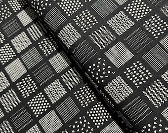 May include: Black and white fabric with a repeating pattern of squares. Each square features a different geometric design, including dots, lines, and letters.