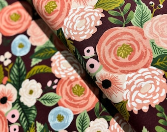 May include: A burgundy fabric with a floral pattern featuring pink, white, and green flowers. The fabric has a soft, textured feel.