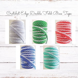 May include: Five spools of double fold bias tape with a crocheted edge. The tape is in various colors including gray, green, red, blue, and teal. Each spool has white polka dots on the tape.