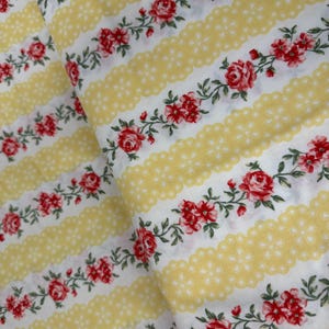 May include: White fabric with yellow and white stripes and a red rose floral pattern.