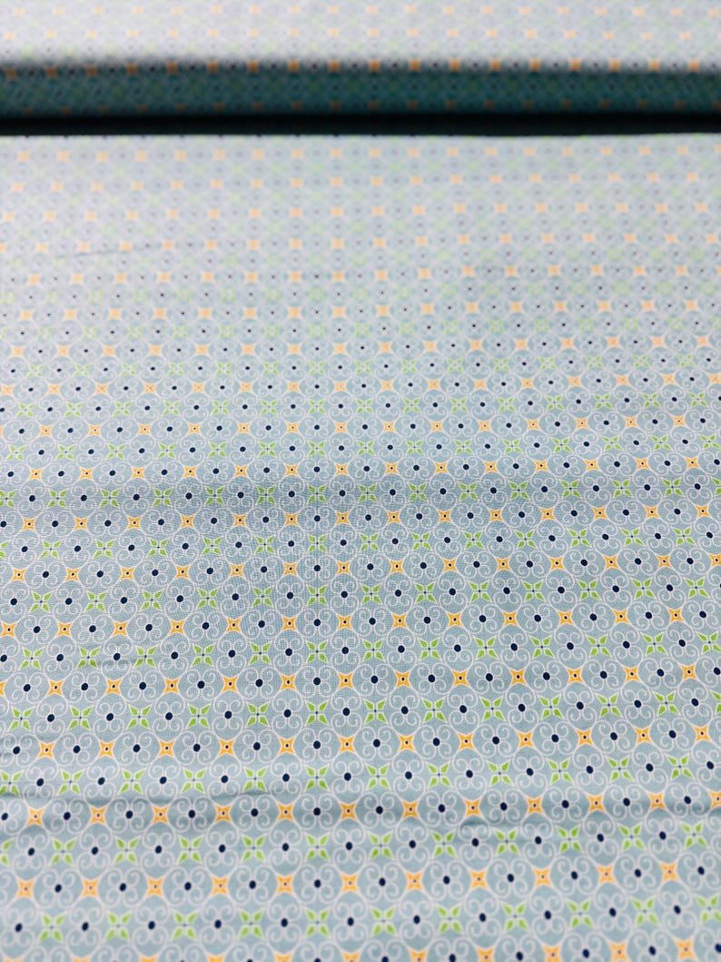 May include: A light blue fabric with a repeating pattern of small yellow, green, and blue shapes. The pattern is a stylized floral design.