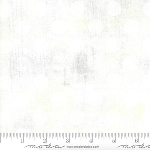 May include: White fabric with a subtle, textured pattern. The fabric has a slightly off-white color with a hint of yellow. The fabric is measured with a ruler in inches.