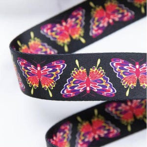 May include: Black ribbon with a repeating butterfly pattern. The butterflies are in shades of red, purple, yellow, and white. Ideal for crafting, gift wrapping, or decorative use.