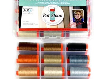 Könnte beinhalten: Eine transparente Plastikbox gefüllt mit 12 Garnrollen in neutralen Farben. Die Box ist mit "The Perfect Box of Neutrals" beschriftet und zeigt den Namen "Pat Sloan" sowie den Text "The Voice of Quilting". Die Box ist auch mit "United Notions" beschriftet.