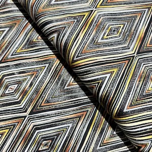 Puede incluir: Tela negra con un patrón geométrico de diamantes dorados, blancos y marrones. La tela tiene un acabado sutilmente brillante.