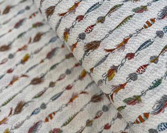 May include: White fabric with a repeating pattern of colorful fishing lures. The lures are in various shapes and sizes, with feathers and hooks. The fabric has a textured surface.