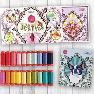 May include: A set of 24 spools of embroidery floss in a variety of colours, arranged in two rows of 12 spools each. The floss is packaged in a white box with a colourful design featuring the text "Thread & Pink" and "Besties" with images of dogs and other animals. The box is open and the spools are visible.