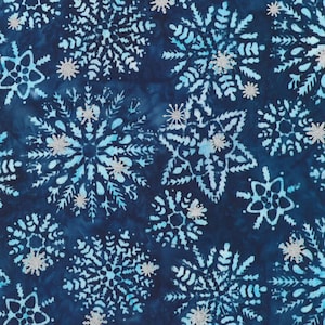 May include: A dark navy blue fabric featuring a repeating pattern of light blue and white snowflakes. The design includes various sizes of intricate, star-shaped snowflake motifs scattered across the surface with a subtle, mottled texture.