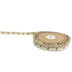 May include: A roll of beige twill ribbon with black measurement markings and the text "Creative Impressions Twill Express". The ribbon extends to the left, showing inch measurements.