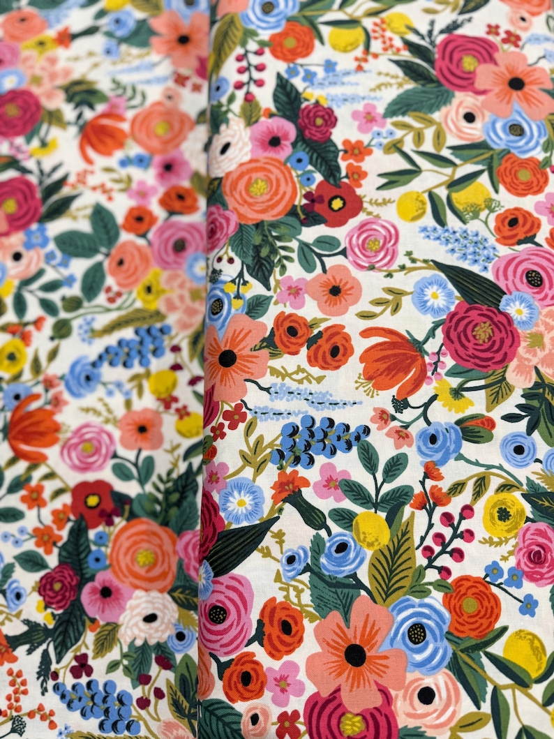 May include: A white fabric with a floral pattern featuring a variety of colorful flowers, including pink, red, orange, yellow, blue, and green.