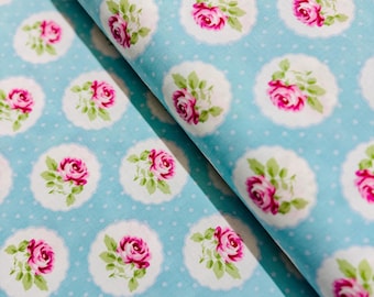 May include: A blue fabric with a white polka dot pattern and a repeating pattern of pink roses in white circles.