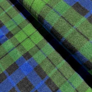May include: Close-up of a green and blue plaid fabric with a soft, fuzzy texture.