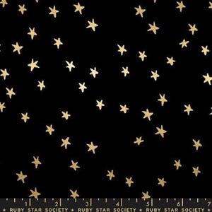 May include: A black fabric featuring a scattered pattern of small gold stars. Along the bottom edge, a white ruler is visible, showing measurements up to 7 inches, with the text Ruby Star Society printed repeatedly along the bottom margin.