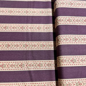 May include: Purple and white striped fabric with a repeating pattern of small red and gray flowers. The fabric has a subtle texture.