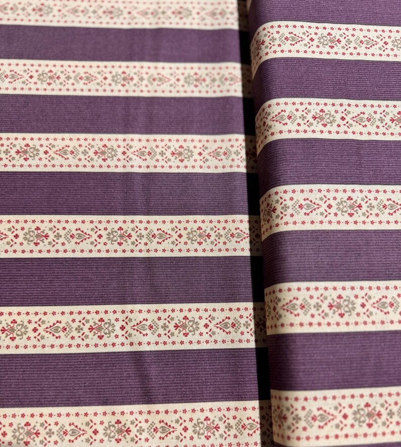 May include: Purple and white striped fabric with a repeating pattern of small red and gray flowers. The fabric has a subtle texture.