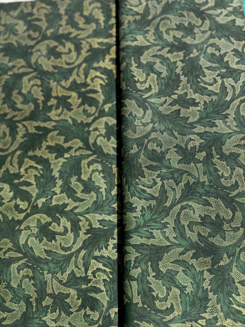 May include: A close-up of a green fabric with a repeating pattern of stylized leaves and dots. The leaves are a darker green and the dots are a lighter green.