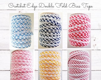 May include: Six spools of double fold bias tape with a crocheted edge. The tape is in various colors and patterns, including blue and white gingham, red and white gingham, pink and white gingham, yellow and white gingham, navy blue and white gingham, and red and white stripes.