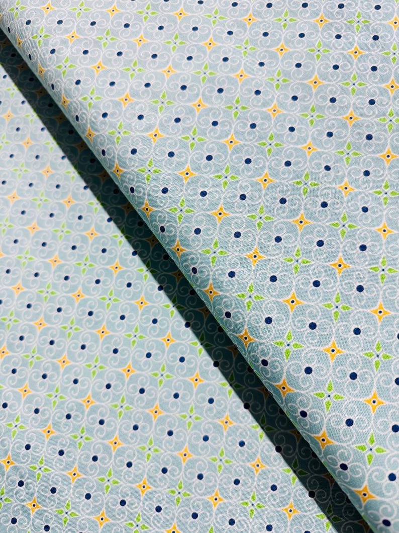 May include: A blue fabric with a repeating pattern of yellow, green, and blue swirls. The fabric has a subtle sheen and a soft texture.