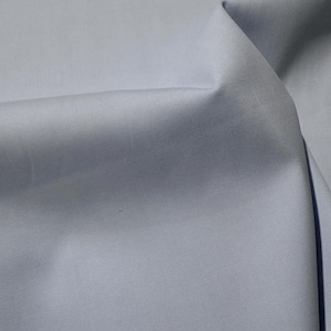 Może przedstawiać: Zbliżenie na jasnoniebieski materiał o gładkiej fakturze. Materiał jest złożony i ma delikatny połysk.