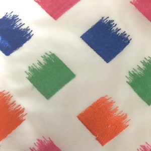 May include: White fabric with a repeating pattern of diamond-shaped embroidered patches in shades of pink, blue, green, and orange.