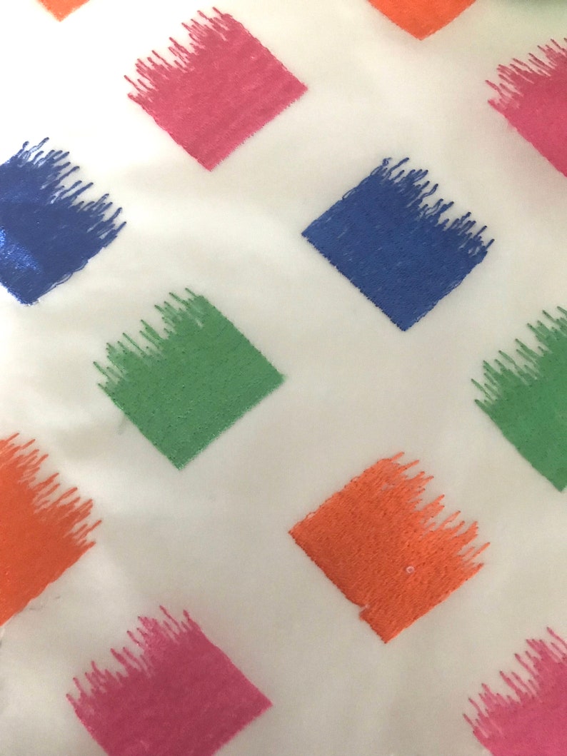 May include: White fabric with a repeating pattern of diamond-shaped embroidered patches in shades of pink, blue, green, and orange.