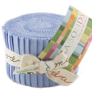 May include: A roll of light blue fabric with a white ribbon tied around it. The fabric is labeled "Moda Solids" and is from the "Moda" brand.