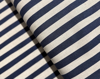 May include: A close-up of a white and navy blue striped fabric. The fabric is folded in half, showing the stripes running in two directions.