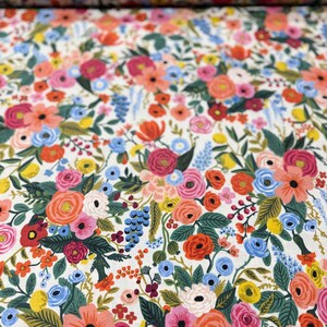 May include: White fabric with a floral pattern featuring a variety of colorful flowers, including pink, red, orange, yellow, blue, and green.