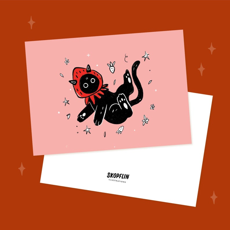 Pode incluir: Um gato preto vestindo uma fantasia de morango vermelho flutua no ar cercado por estrelas brancas e flores em um fundo rosa. O texto "SKOPFLIN ILLUSTRATIONS" est&aacute; em um fundo branco abaixo da imagem.