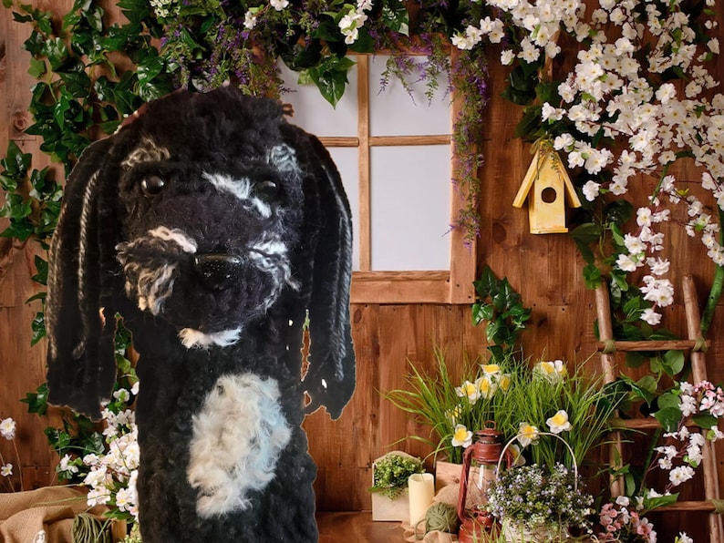 May include: A black and white plush dog toy with long, floppy ears. The dog has a white patch on its chest and a fluffy muzzle. The background features a wooden wall, a window, and floral decorations, creating a whimsical scene.
