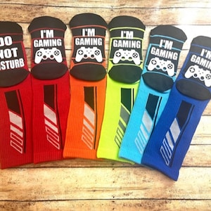 May include: Six pairs of colorful socks with different designs. One pair says "Do Not Disturb" and the other five pairs say "I'm Gaming" with a video game controller graphic.