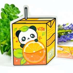 May include: A sticker depicting a panda peering over a sliced orange, set against a yellow juice box. The box has the words "Vita" and "Lemon" printed on it. The design includes green leaves, hearts, and a white straw. The sticker is a fun, colourful design.