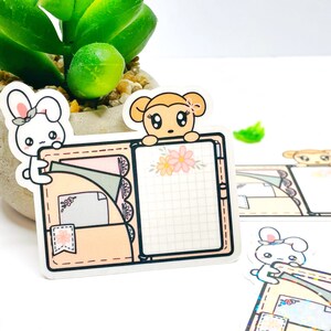 May include: A sticker depicting a light peach planner with a grid page and pockets. A cartoon bunny and monkey are positioned above the planner. The planner is decorated with floral and decorative elements.