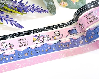 Può includere: Una collezione di rotoli di nastro adesivo decorativo washi con vari disegni. I nastri presentano illustrazioni di nuvole, stelle e simpatici personaggi. Un nastro ha il testo "LET YOUR dreams COME TRUE". La tavolozza dei colori comprende nero, rosa, blu e argento.