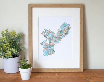 Pode incluir: Uma impressão emoldurada de um mapa de uma cidade com bairros delineados em azul, rosa e dourado. Os bairros são etiquetados com nomes em uma fonte manuscrita.
