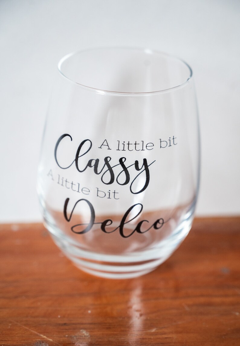 Puede incluir: Una copa de vino de vidrio transparente con el texto "A little bit Classy A little bit Delco" impreso en el lateral.