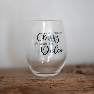 Puede incluir: Una copa de vino de vidrio transparente con el texto "A little bit Classy, A little bit Delco" impreso en el lateral.