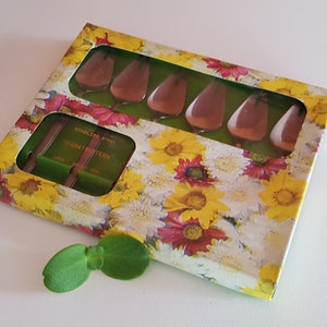 May include: A set of six stainless steel butter knives in a floral patterned box. The knives are arranged in a row and are all the same size. The box is made of cardboard and has a clear plastic window so you can see the knives.