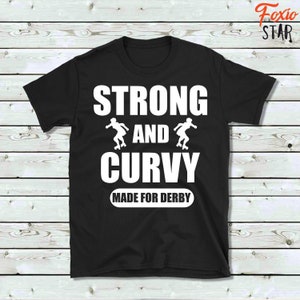 Puede incluir: Camiseta negra con texto blanco que dice "Strong and Curvy Made for Derby". El texto est&aacute; rodeado por dos siluetas blancas de patinadoras de roller derby.