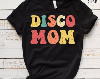 May include: Black t-shirt with a retro-style graphic that says "DISCO MOM" in colorful letters.