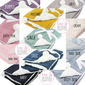May include: Ten different colors of baby blankets with a cable knit pattern and a white sherpa lining. The blankets are arranged in a circle with the brand name "Love Jo Designs" on each blanket.