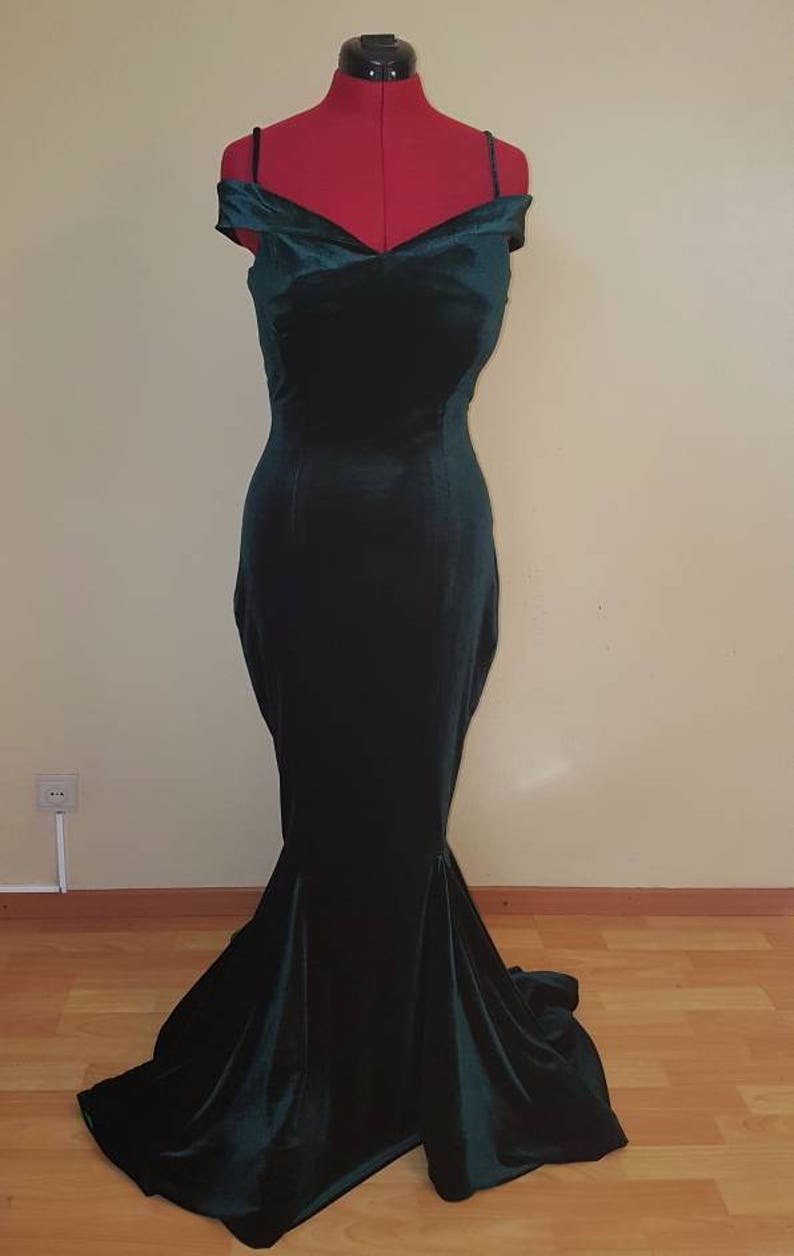May include: A dark green velvet off-the-shoulder gown with a fitted bodice and a flowing mermaid skirt.