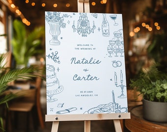 May include: A white wedding sign with blue illustrations of a cake, champagne glasses, candles, and flowers. The sign reads "Welcome to the wedding of Natalie & Carter 06.07.2024 Los Angeles, CA".