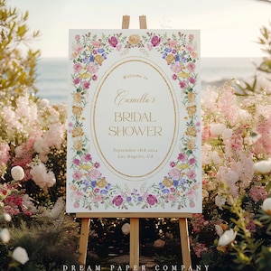 Puede incluir: Un cartel blanco con un marco dorado y un borde floral. El cartel dice "Bienvenido al Bridal Shower de Camilla, 18 de septiembre de 2023, Los &Aacute;ngeles, CA".