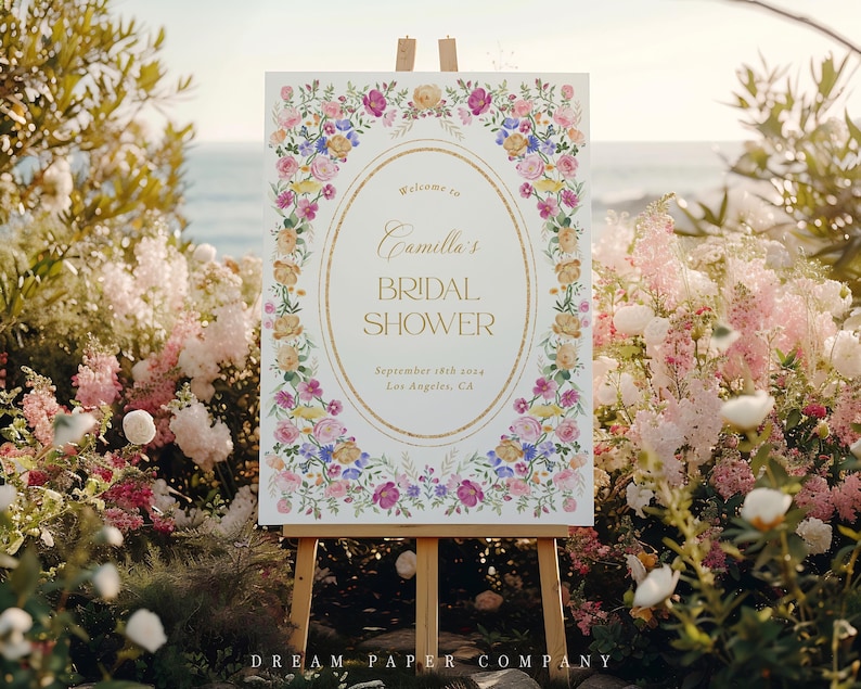 Puede incluir: Un cartel blanco con un marco dorado y un borde floral. El cartel dice "Bienvenido al Bridal Shower de Camilla, 18 de septiembre de 2023, Los &Aacute;ngeles, CA".