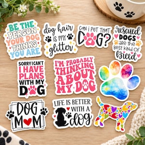 May include: A collection of ten die-cut vinyl stickers featuring dog-themed phrases and illustrations. Designs include text like Be the person your dog thinks you are, Dog hair is my glitter, Can I pet that dog, Rescued dogs are the best kind of breed, Sorry I can't I have plans with my dog, I'm probably thinking about my dog, Dog mom, and Life is better with a dog, alongside a colorful watercolor paw print and a heart-patterned dog silhouette.