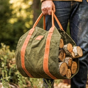 May include: A green canvas bag with brown leather straps and handles, filled with logs of firewood.